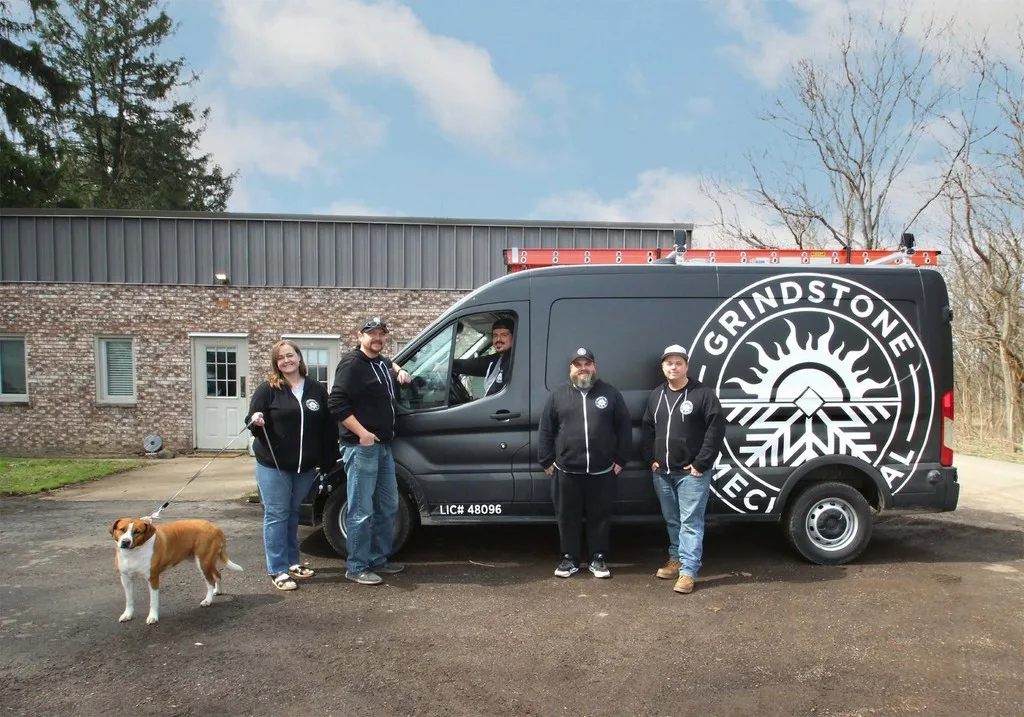 Grindstone Mechanical crew lined up in front of a white service van with the company logo.