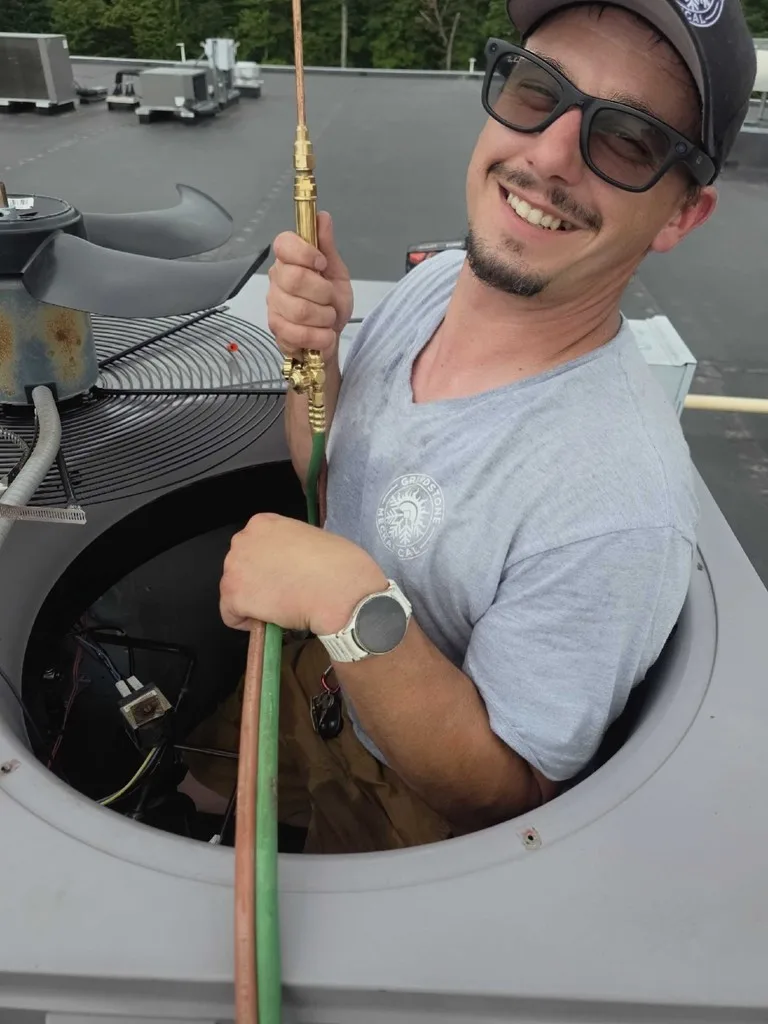 Smiling technician in sunglasses looking out from inside an open condenser cabinet.